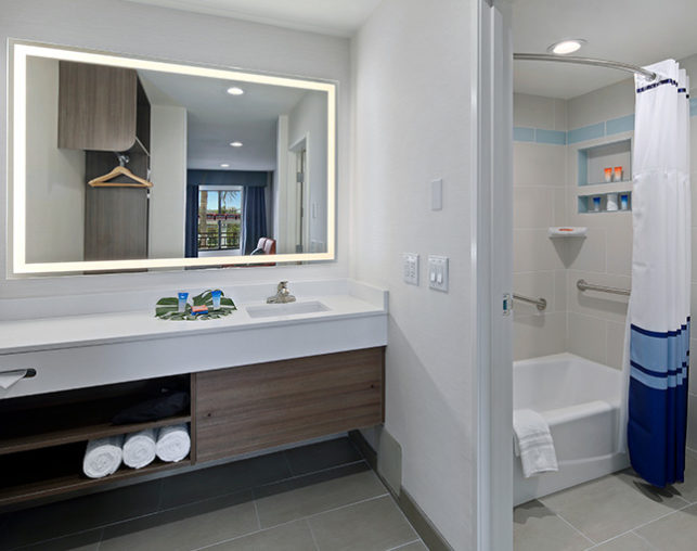 A spacious bathroom featuring a well-lit mirror, custom bath amenities & shower at our hotel near Disneyland