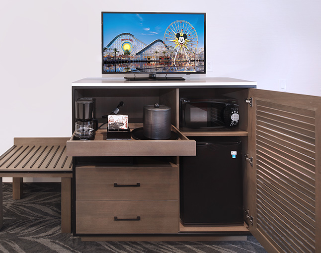 A room amenity setup with a TV, coffee maker, microwave, and mini fridge.