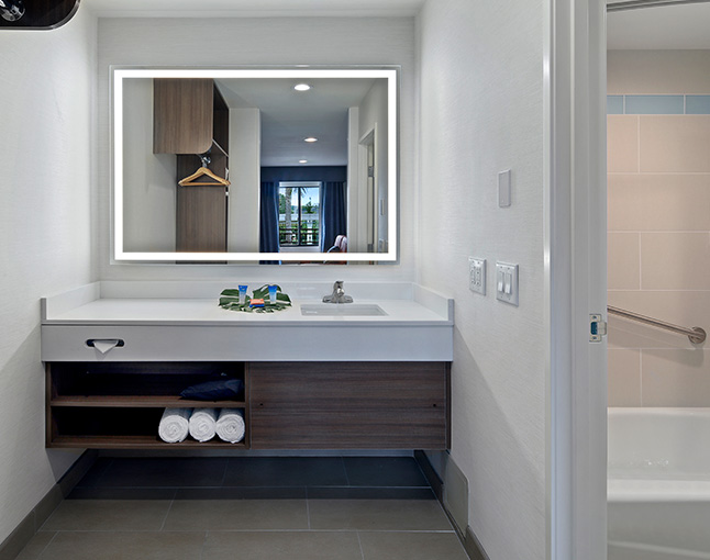 A bathroom with a sink, mirror, towels, and a bathroom door
