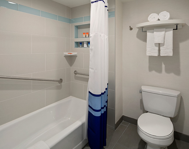 A bathroom with a bathtub, toilet, and shower curtain.