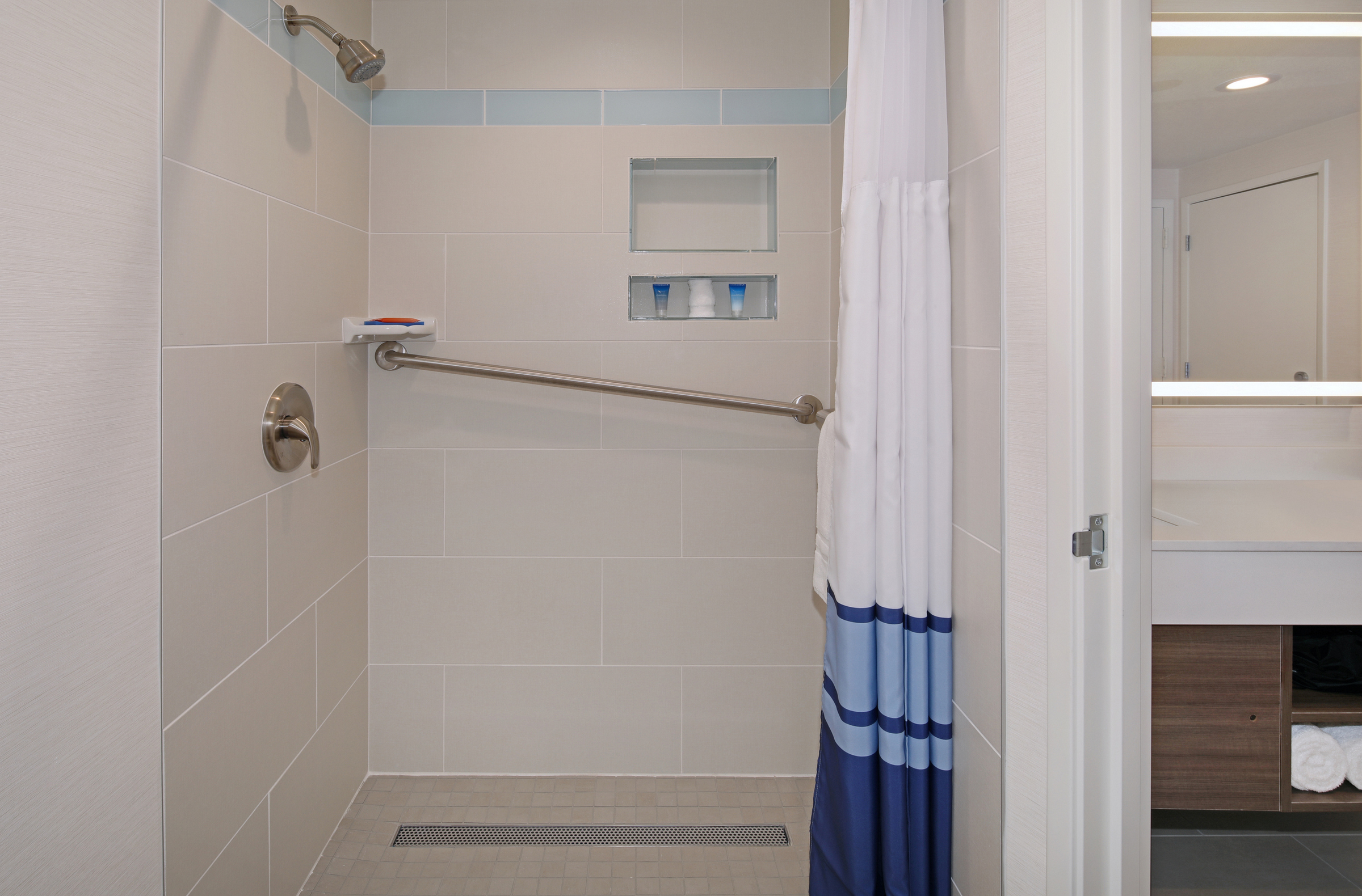 A bathroom shower with a grab bar, shower curtain, and tile walls
