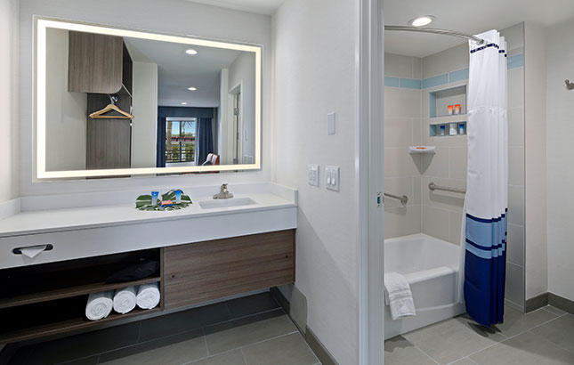 A clean bathroom with a sink, mirror, shower, and bathtub