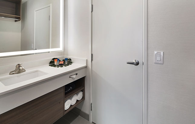 A bathroom sink and mirror with towels and toiletries.