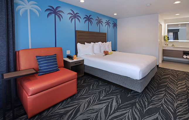 A hotel room with a bed, chair, and nightstand.