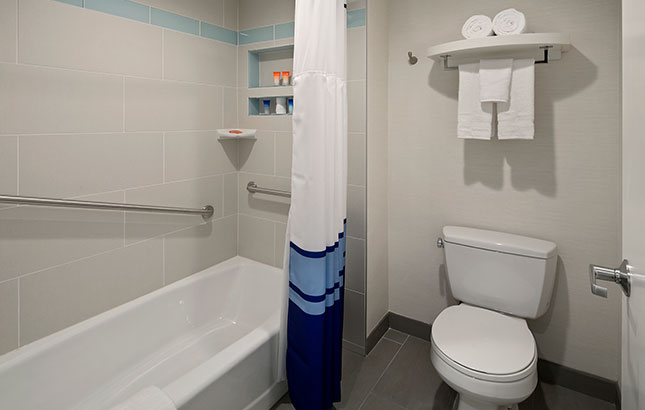 A clean bathroom with a bathtub, toilet, and shower curtain.