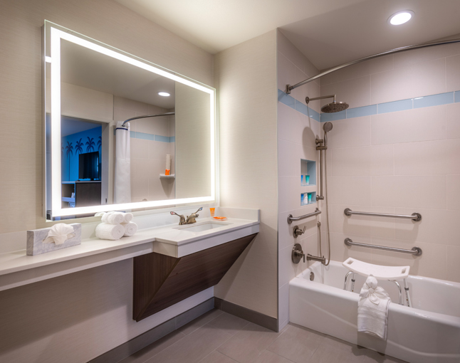 A clean bathroom with a large mirror, sink, bathtub, and shower.