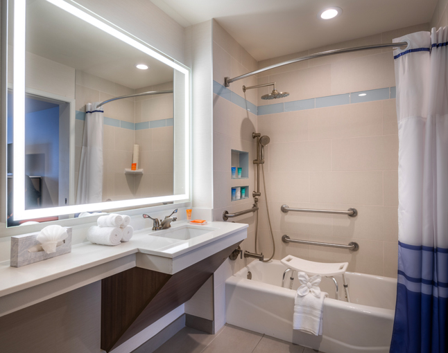 A clean bathroom with a bathtub, shower, sink, and large mirror