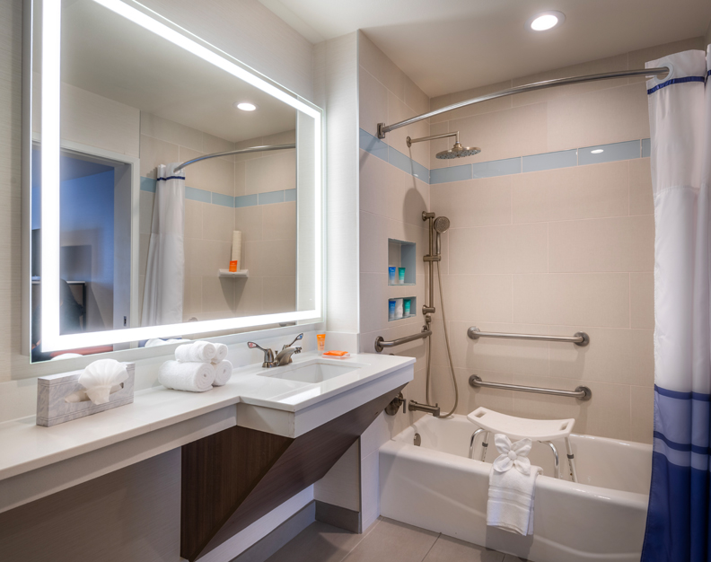 A clean bathroom with a large mirror, sink, bathtub, and shower.