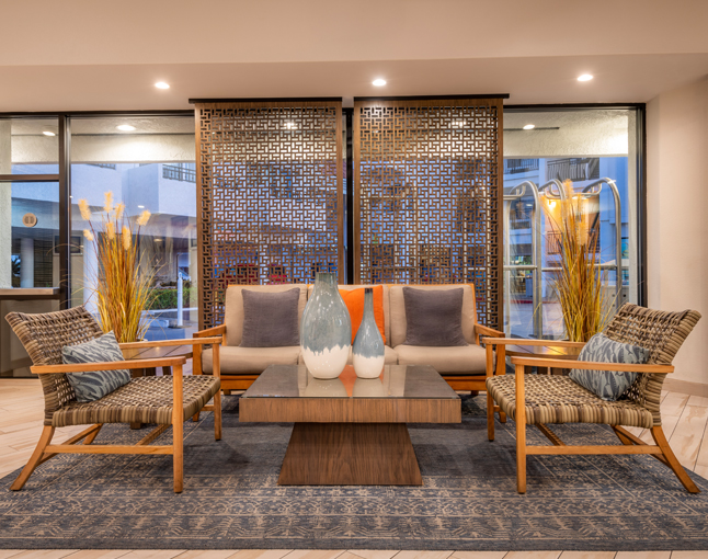 A lobby lounge with a sofa, chairs, coffee table, and decorative vases.