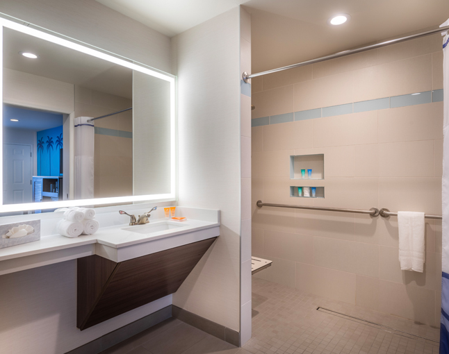 A clean bathroom with a sink, mirror, and shower.
