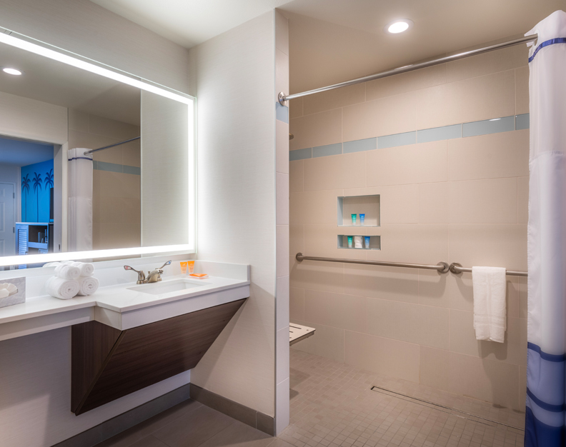 A bathroom with a shower, sink, and mirror.